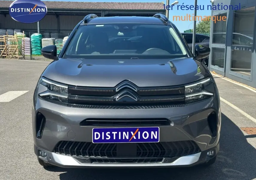 Vue frontale d'un Citroën C5 Aircross gris Platinium 2025 avec calandre distinctive et barres de toit visibles.