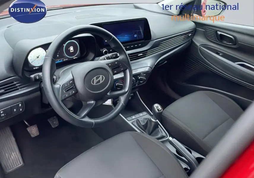 Intérieur noir de la Hyundai i20 2025, vue côté conducteur montrant volant cuir, tableau de bord digital et boîte manuelle.