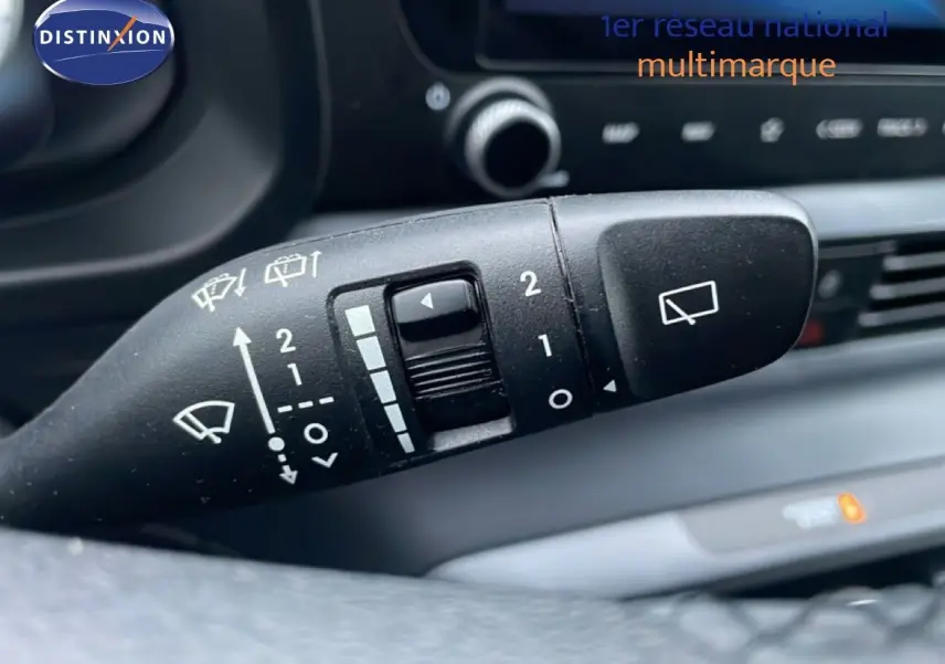 Gros plan sur la commande d'essuie-glace du volant d'une Hyundai i20 rouge Dragon Metal, intérieur noir visible en arrière-plan.