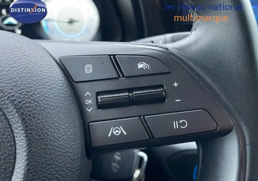 Gros plan sur les commandes de régulateur de vitesse au volant cuir noir de la Hyundai i20 Rouge Dragon Metal 2025.