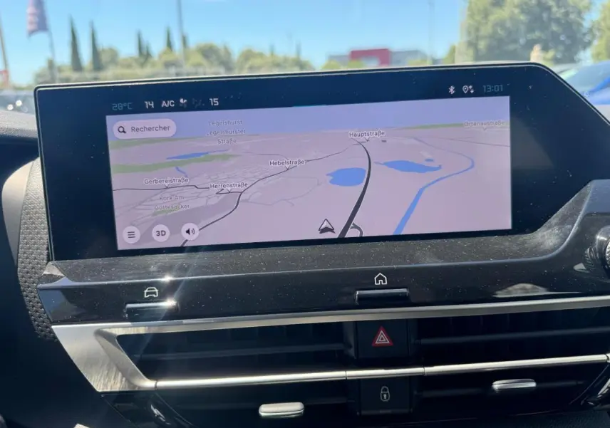 Écran tactile central du tableau de bord de la Citroën C4 hybride blanche, affichant la navigation GPS en plein jour.