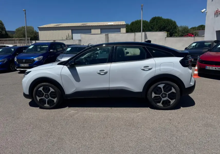 Vue de profil côté gauche d'une Citroën C4 hybride blanche avec toit noir et jantes alliage 18 pouces.