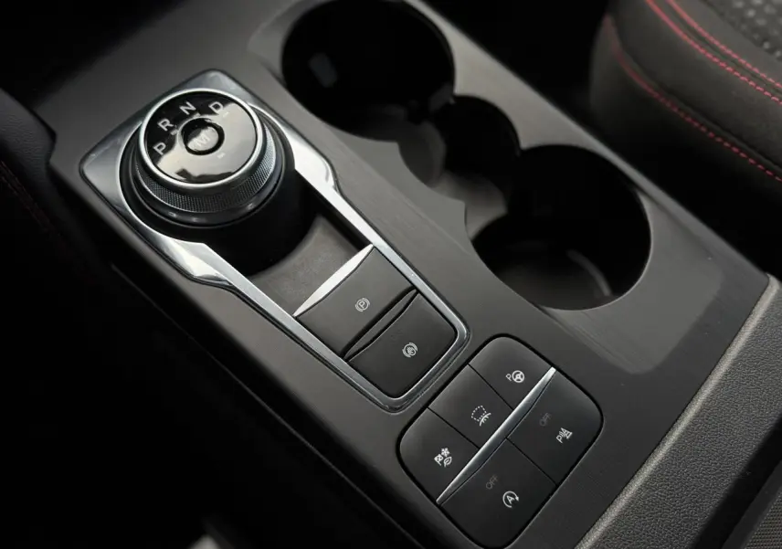 Gros plan sur la console centrale noire du Ford Kuga 2023 avec sélecteur rotatif de vitesse et boutons de contrôle.