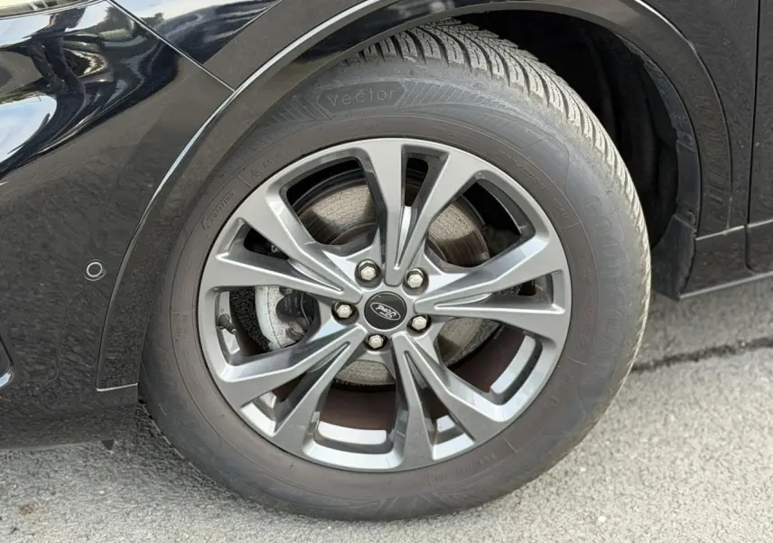 Gros plan sur la roue avant gauche du Ford Kuga noir Agathe avec jante alliage 18 pouces 5x2 branches ST-Line.