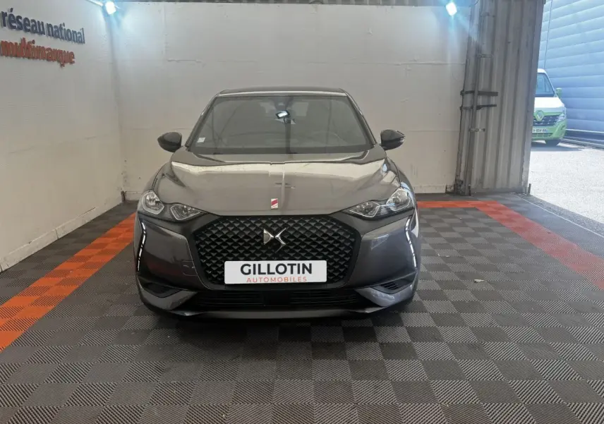 Vue frontale d'un DS3 Crossback gris foncé avec calandre hexagonale et logo DS bien visible.