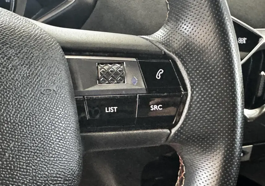Gros plan sur le volant en cuir perforé du DS3 Crossback gris foncé, avec commandes multifonctions visibles.