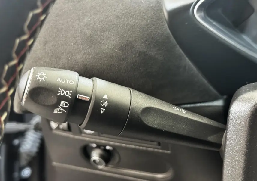 Gros plan sur la commande des feux et clignotants à gauche du volant cuir dans un DS3 Crossback gris foncé 2021.