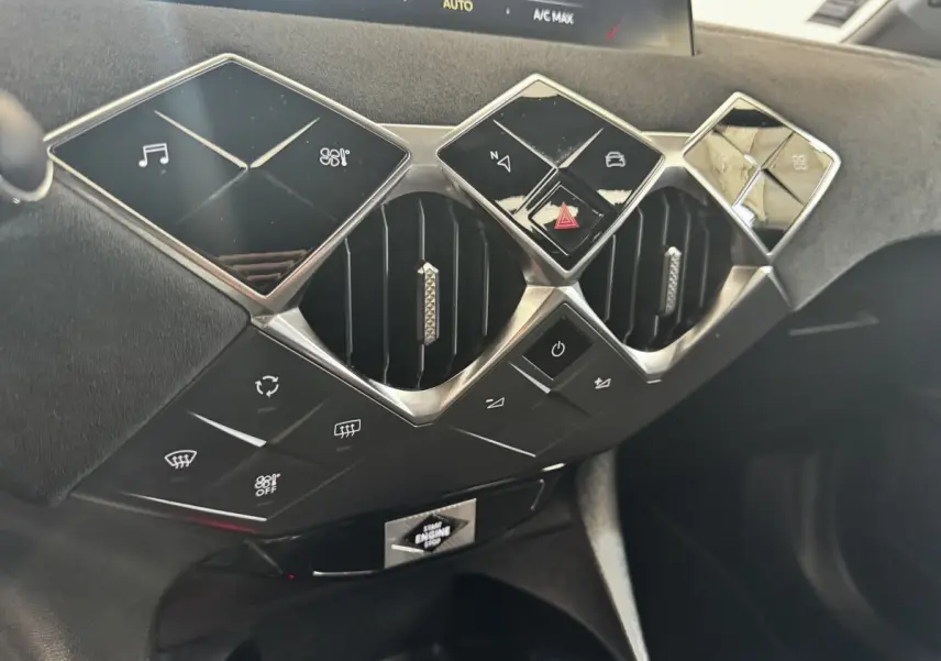 Gros plan sur la console centrale du DS3 Crossback gris foncé, mettant en valeur les boutons carrés et les aérateurs hexagonaux chromés.