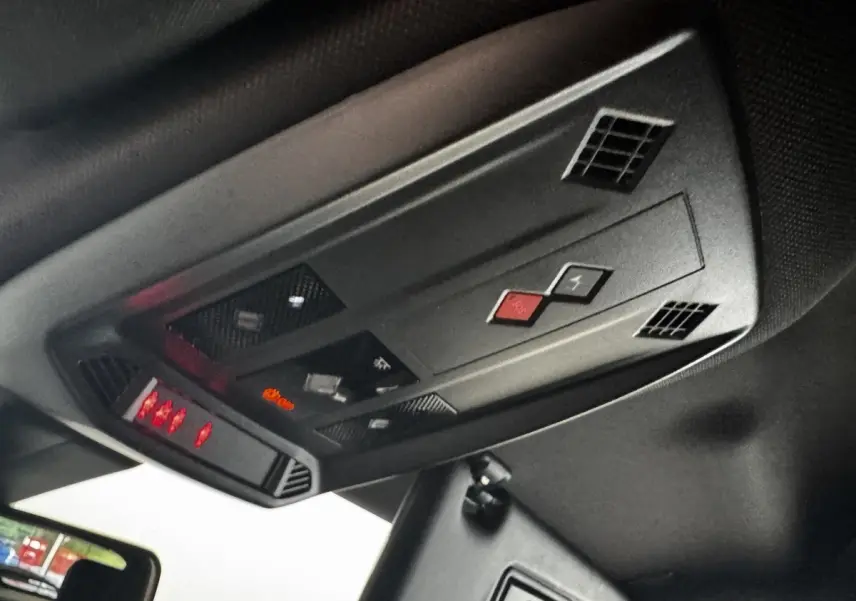 Vue en contre-plongée du plafonnier noir avec commandes et voyants rouges du DS3 Crossback gris foncé 2021.