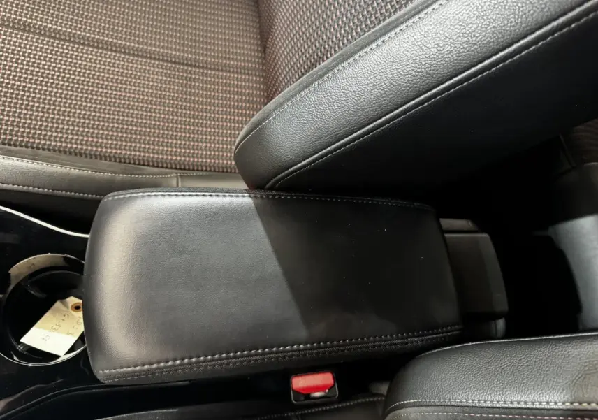Gros plan sur l'accoudoir central en cuir noir et la console entre les sièges avant du DS3 Crossback gris foncé.