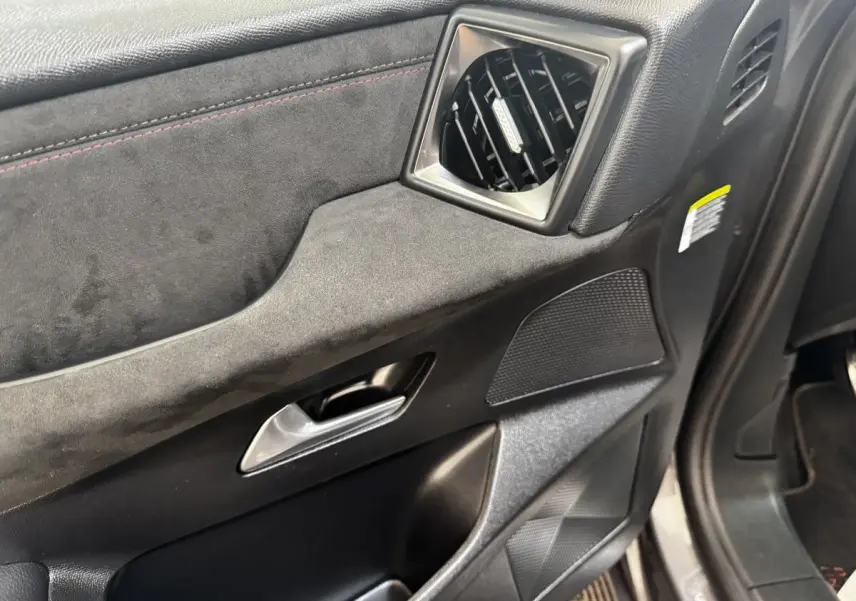 Gros plan sur la porte avant gauche intérieure du DS3 Crossback gris foncé, avec garniture en alcantara et sortie d'air carrée.