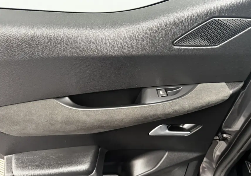 Gros plan sur la porte côté gauche du DS3 Crossback gris foncé, montrant la poignée, le bouton de verrouillage et un insert en tissu gris.