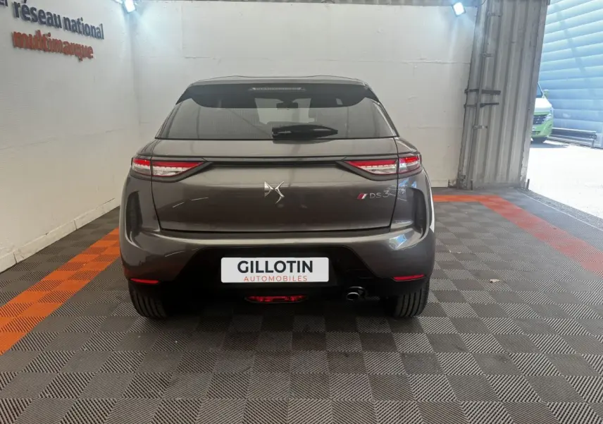 Vue arrière d'un DS3 Crossback gris foncé avec feux LED étirés et logo DS centré, en intérieur showroom.