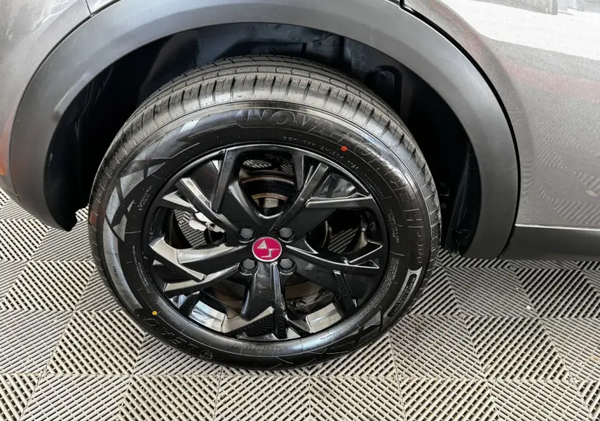 Gros plan sur la roue arrière droite du DS3 Crossback gris foncé, mettant en valeur la jante noire au logo DS rouge.