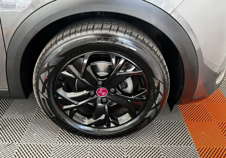 Gros plan sur la roue avant droite du DS3 Crossback gris foncé avec jante noire brillante et logo DS rouge.