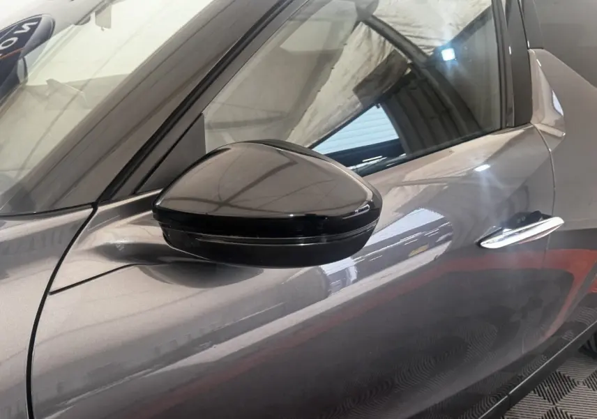 Gros plan sur le rétroviseur côté gauche d’un DS3 Crossback gris foncé, avec reflet de l’environnement intérieur.