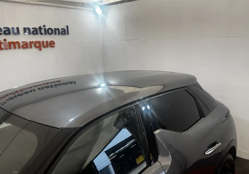 Vue 3/4 arrière droite du DS3 Crossback gris foncé avec vitres teintées et poignées de porte chromées.