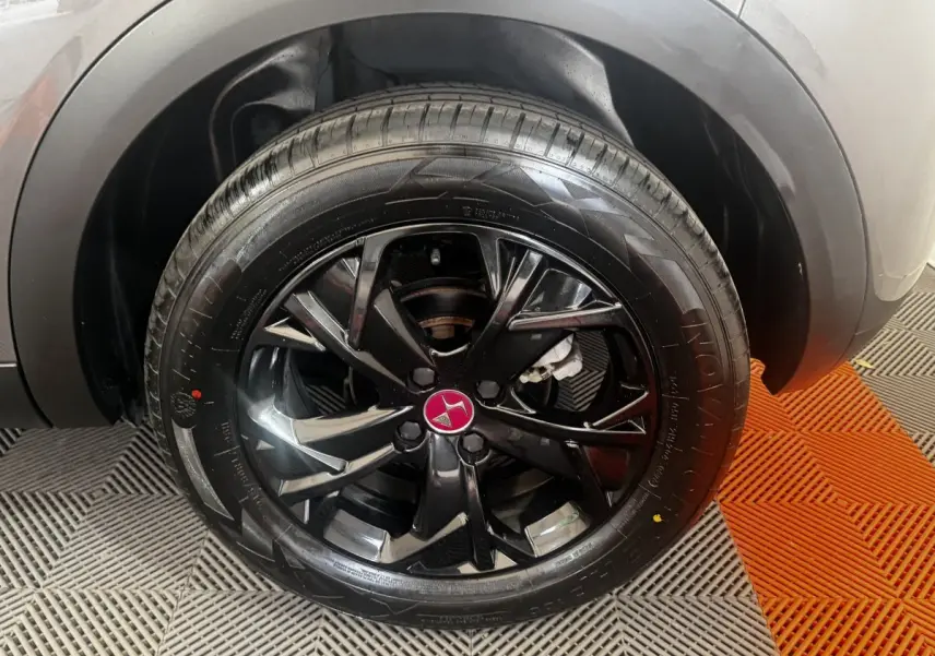 Gros plan sur la roue avant droite du DS3 Crossback gris foncé avec jante noire brillante et logo DS rouge au centre.