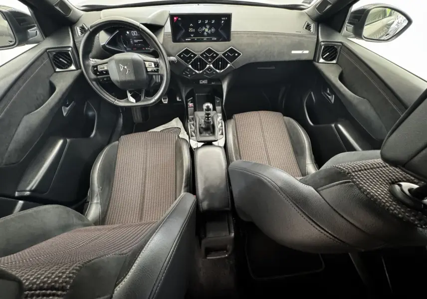 Vue intérieure avant du DS3 Crossback gris foncé, volant cuir multifonctions, écran tactile central et sièges tissu cuir bicolores.