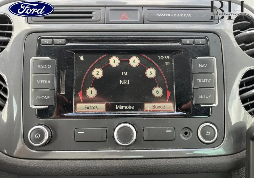 Vue rapprochée de la console centrale grise d’un Volkswagen Tiguan 2014 avec écran tactile et commandes radio visibles.