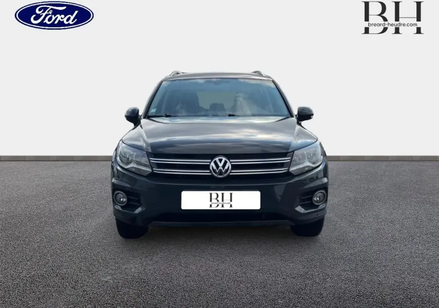 Vue avant d'un Volkswagen Tiguan gris poivre avec calandre chromée et phares halogènes visibles.