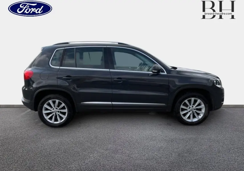 Vue de profil côté gauche d'un Volkswagen Tiguan gris poivre avec jantes alliage sur fond neutre.