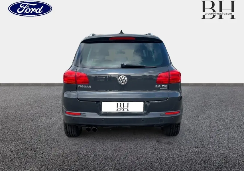 Vue arrière d'un Volkswagen Tiguan gris poivre avec double sortie d'échappement et feux rouges allongés.