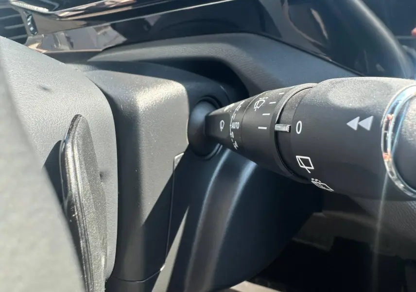 Gros plan sur la commande des essuie-glaces côté droit du volant dans l’habitacle noir du Peugeot 308 SW blanc.