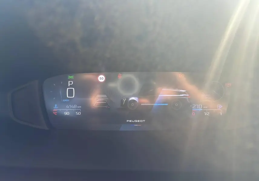 Tableau de bord numérique du Peugeot 308 SW hybride, affichant la vitesse, autonomie et indicateurs, avec reflet lumineux.