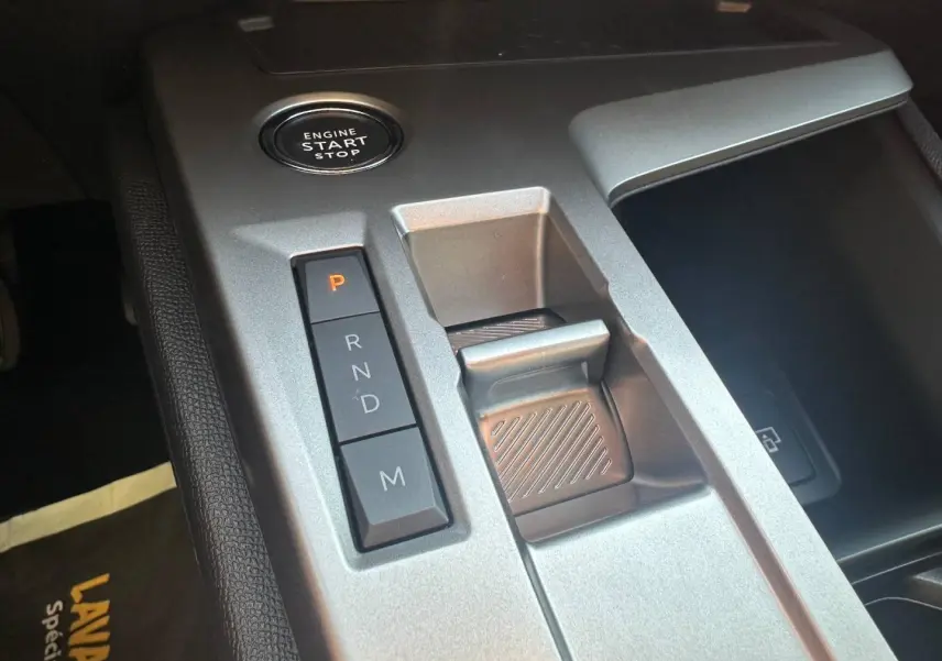 Gros plan sur la console centrale grise de la Peugeot 308 SW Hybrid avec bouton start/stop et commandes de boîte automatique.