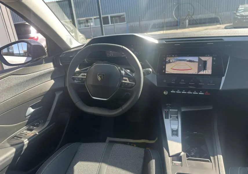 Vue intérieure avant de la Peugeot 308 SW blanche, avec volant multifonction et écran tactile affichant la caméra de recul.