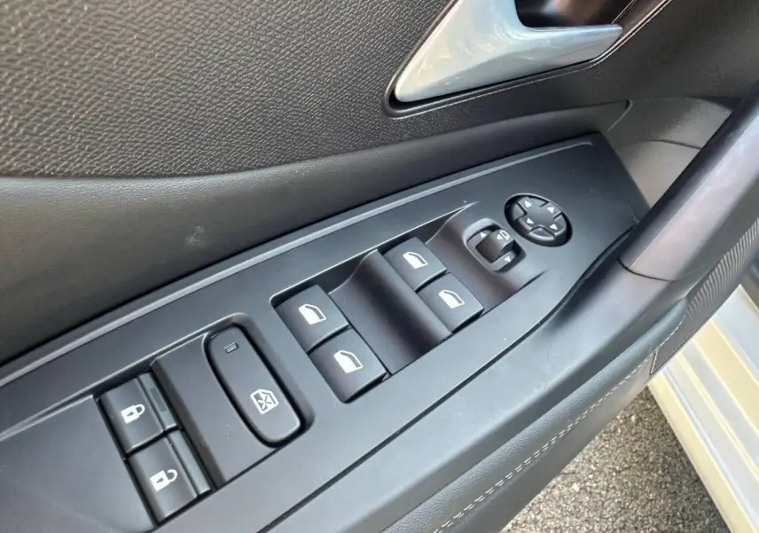 Gros plan sur la commande des vitres et rétroviseurs côté conducteur d’une Peugeot 308 SW blanche.