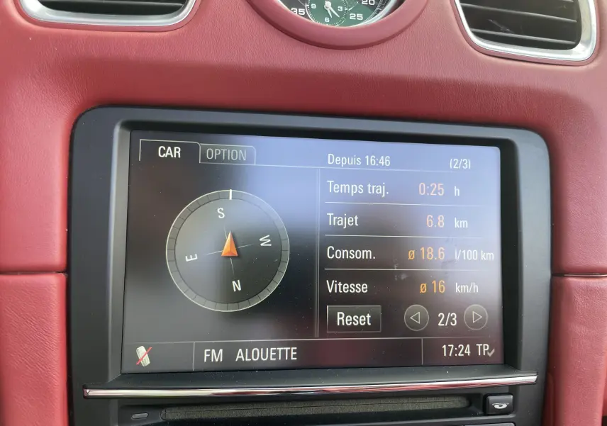 Écran central de la Porsche Boxster S 981 2012 montrant la consommation, vitesse et trajet, entouré de cuir rouge grenat.