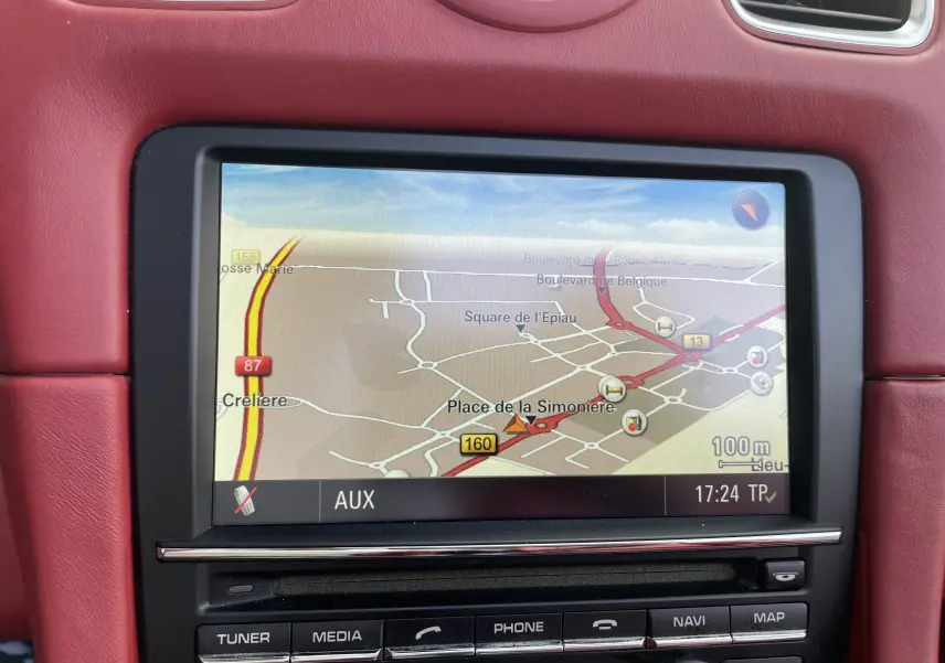 Écran de navigation allumé dans l'habitacle cuir rouge grenat d'une Porsche Boxster S 981 de 2012.