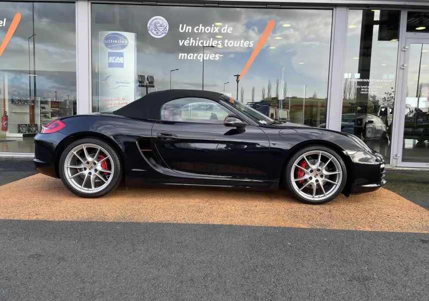 Profil latéral droit d'une Porsche Boxster S 981 noire intense avec capote noire et jantes Carrera S 20 pouces argentées.