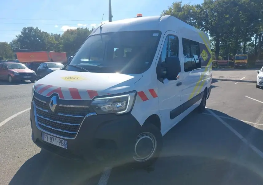 Renault Master blanc en 3/4 avant droit avec marquages rouges et jaunes et gyrophare sur le toit.