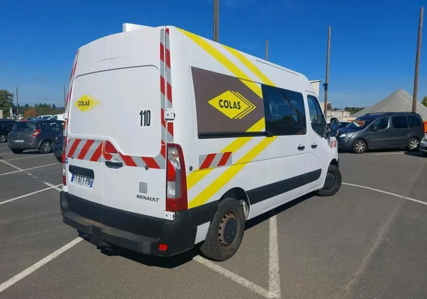 Renault Master cabine approfondie blanc, vue 3/4 arrière droit, marquages jaunes et rouges COLAS et gyrophare visible.