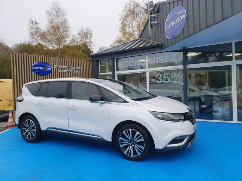 Renault Espace blanc nacré vu de profil côté gauche, avec jantes alliage et vitres arrière surteintées devant un showroom.