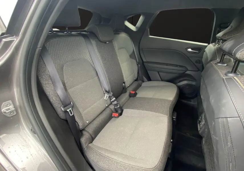 Vue intérieure côté gauche des sièges arrière gris tissu du Renault Captur 2025 avec ceinture de sécurité et porte fermé.