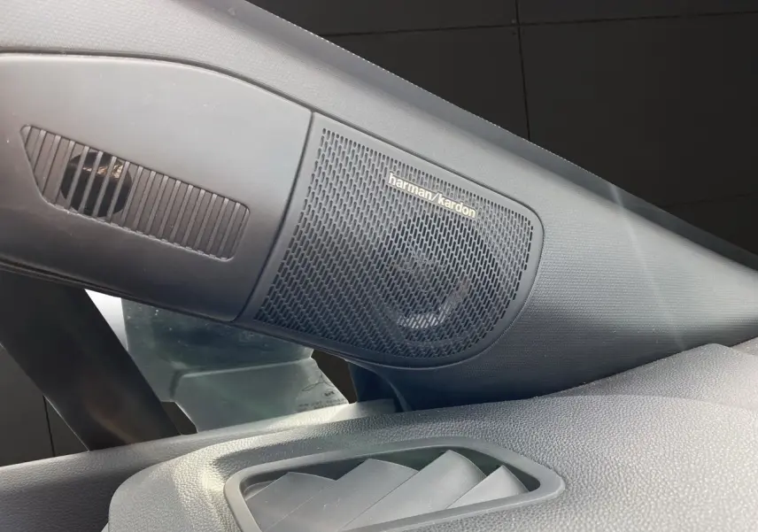 Gros plan sur l'enceinte Harman/Kardon intégrée côté gauche du tableau de bord du Renault Captur gris Cassiopée.