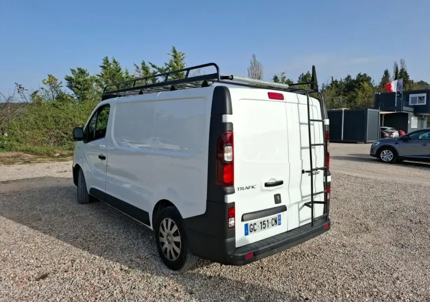 Vue 3/4 arrière droite du fourgon blanc Renault Trafic L1H1 2021 avec galerie et échelle noire sur toit.