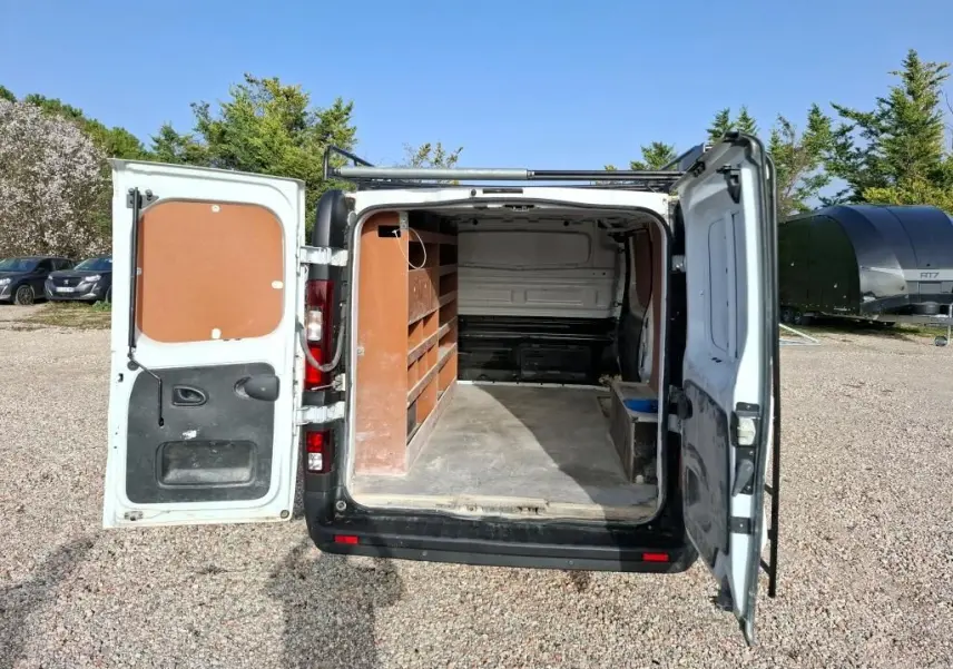 Vue arrière du Renault Trafic Fourgon blanc 2021 avec portes ouvertes montrant l'aménagement intérieur en bois.