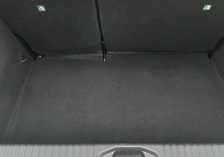 Coffre vide vu de dessus de la Renault Clio V gris schiste, montrant le revêtement intérieur noir et les dossiers arrière rabattables.