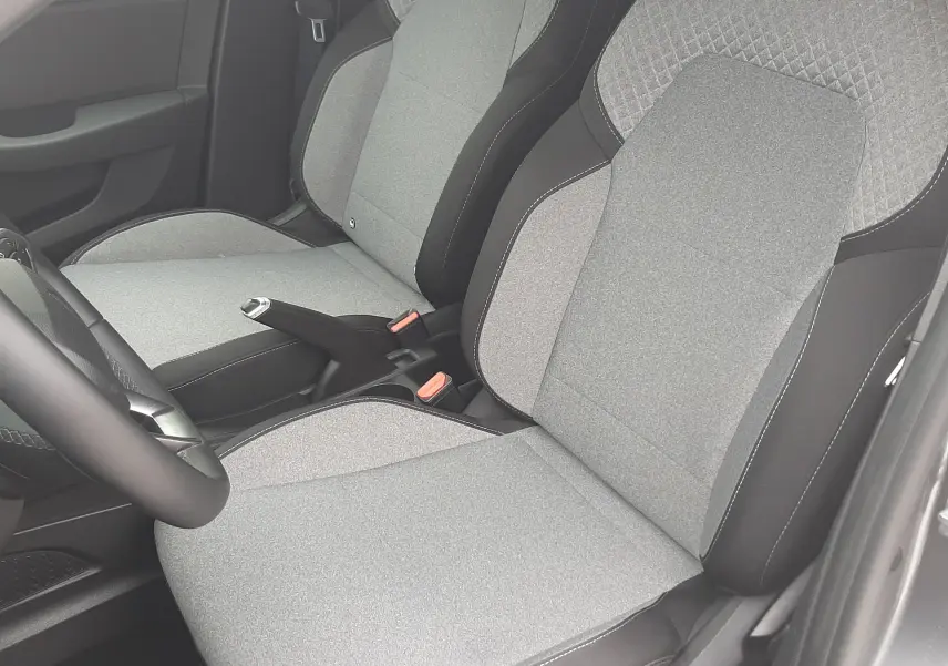 Vue intérieure rapprochée des sièges avant gris clair et noir de la Renault Clio V 2025, tissu avec surpiqûres.