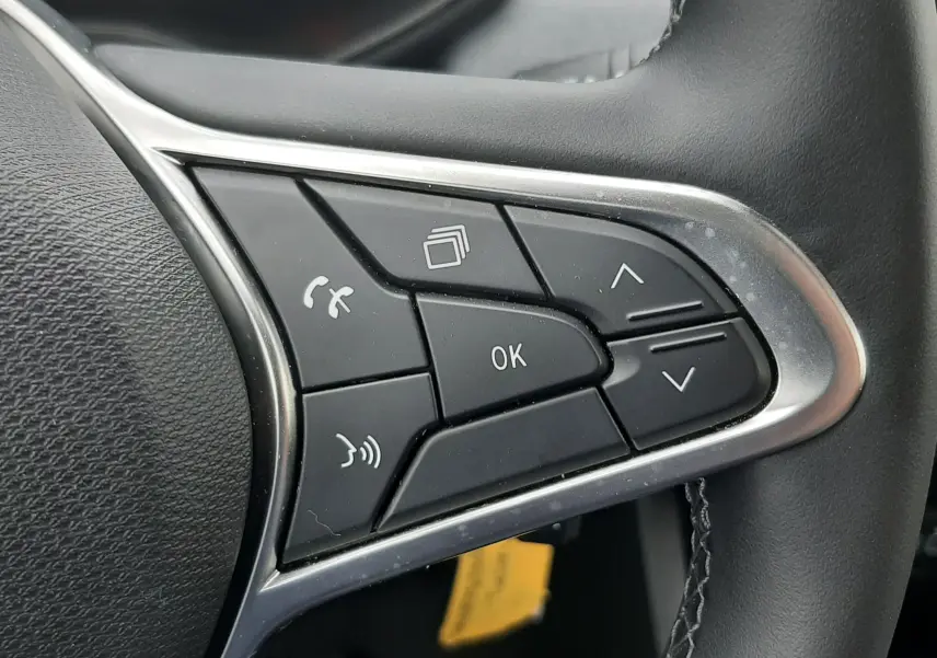 Gros plan sur les commandes multifonctions à droite du volant noir de la Renault Clio V gris schiste, avec boutons de navigation et téléphone.