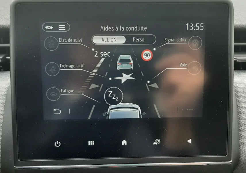 Écran central de la Renault Clio V gris schiste montrant les aides à la conduite avec affichage digital en vue frontale.