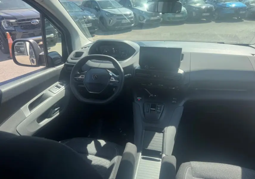 Vue intérieure avant du Peugeot Rifter gris 2026, montrant le volant multifonctions, l'écran tactile et la console centrale.