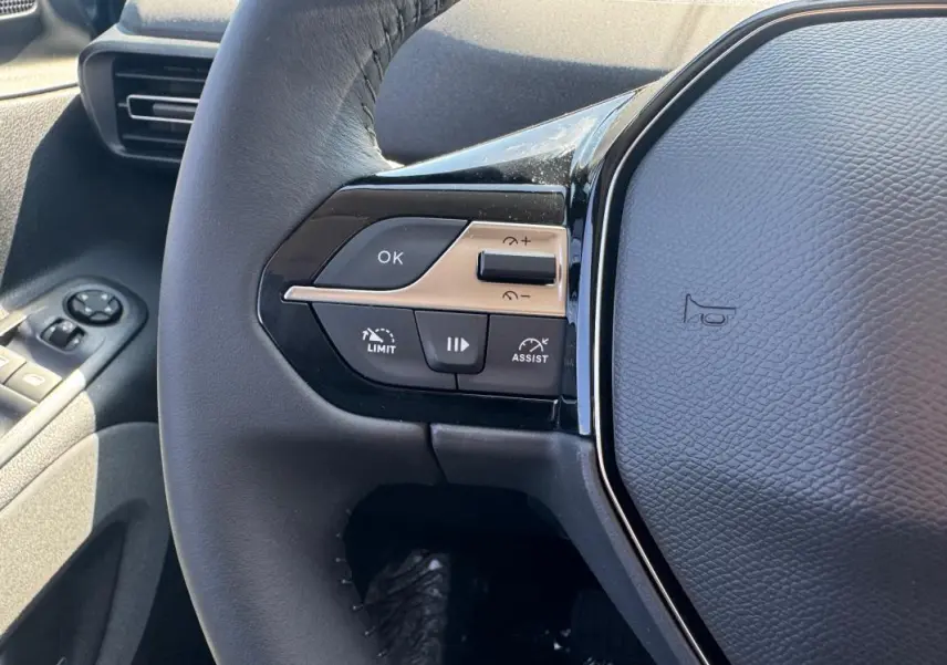 Gros plan sur le volant cuir gris du Peugeot Rifter 2026, avec commandes multifonctions et boutons de limitation de vitesse.