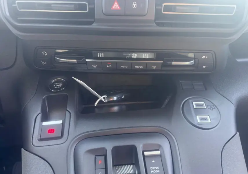 Vue rapprochée du tableau de bord et console centrale du Peugeot Rifter gris 2026, avec commandes climatisation et bouton start-stop.
