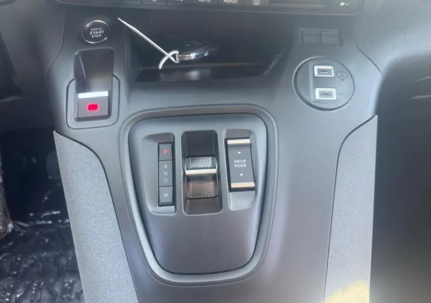 Gros plan sur la console centrale noire du Peugeot Rifter 2026 avec levier de vitesse automatique et boutons de mode de conduite.